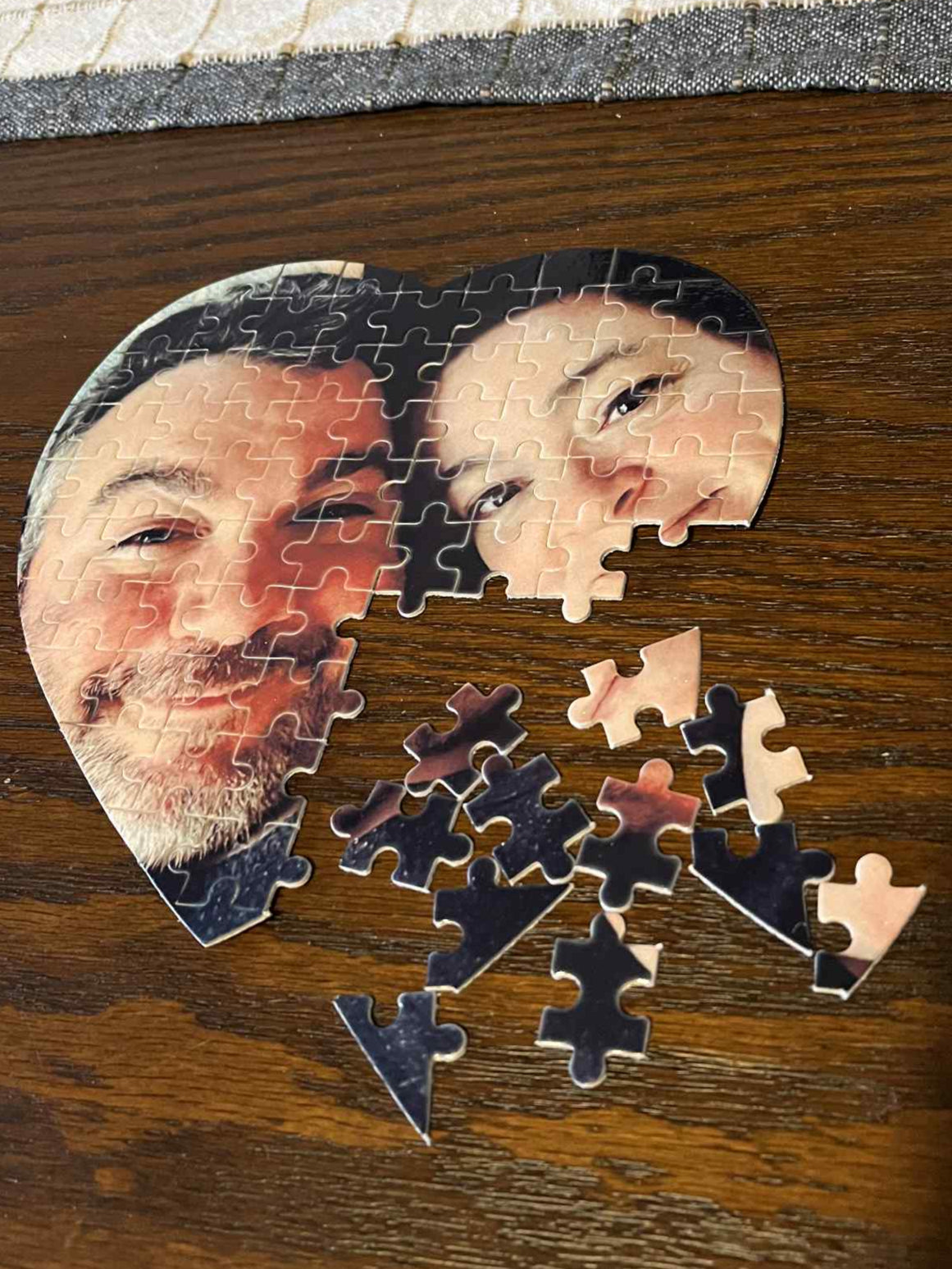 Heart-shaped puzzle with a couple's faces on a wooden surface