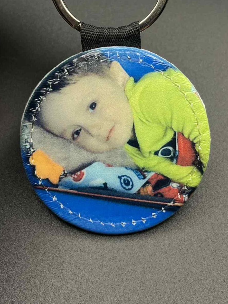 Round keychain with a plush toy and a child's face on a blue background